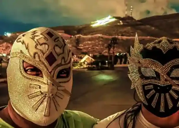 Two lucha libre wrestlers in gold masks in front of the El Paso star