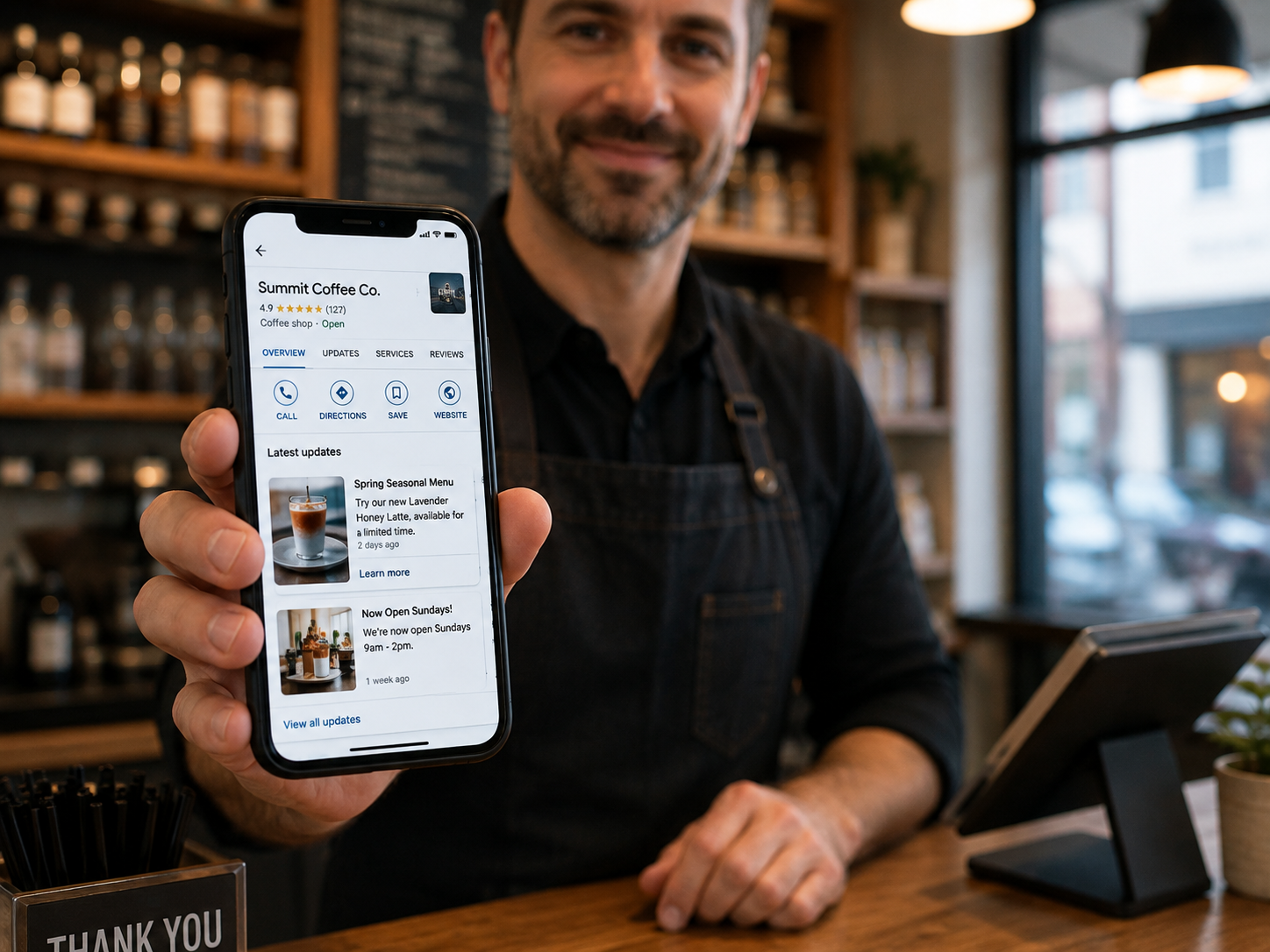 Small business owner holding a phone showing a local business listing behind a tidy service counter
